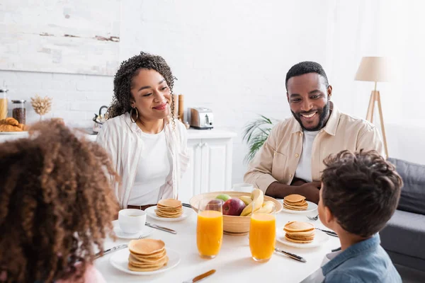 Familia afroamericana feliz desayunando en la cocina - foto de stock
