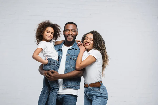 Cheerful african american family smiling at camera on grey — Stock Photo