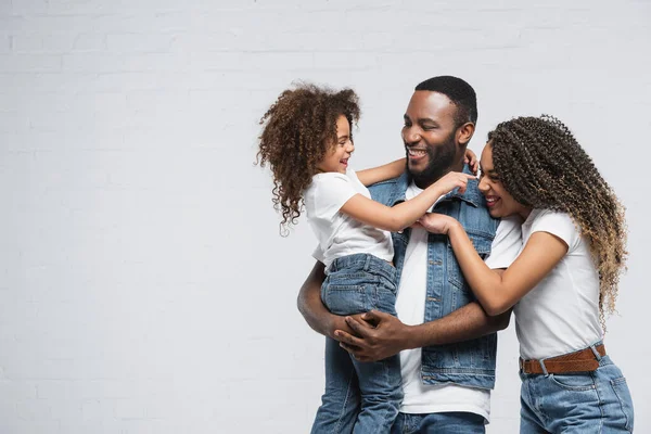 Excited african american family looking at each other and hugging on grey — Stock Photo