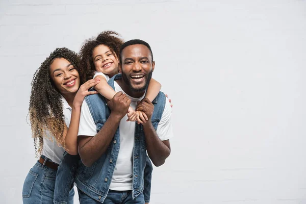 Glückliche afrikanisch-amerikanische Familie schaut in die Kamera, während sie sich auf grau umarmt — Stockfoto