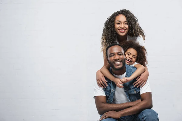 Allegra donna afroamericana con figlia che abbraccia l'uomo felice sul grigio — Foto stock