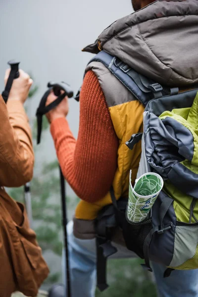 Map in backpack of man standing near woman — Stock Photo