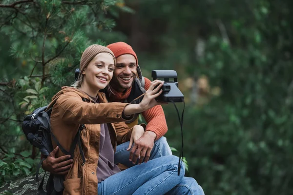Cheerful couple taking selfie on vintage camera in forest — Stock Photo