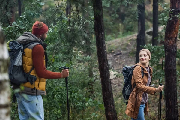 Zufriedenes Paar schaut sich beim Trekking mit Wanderstöcken im Wald an — Stockfoto