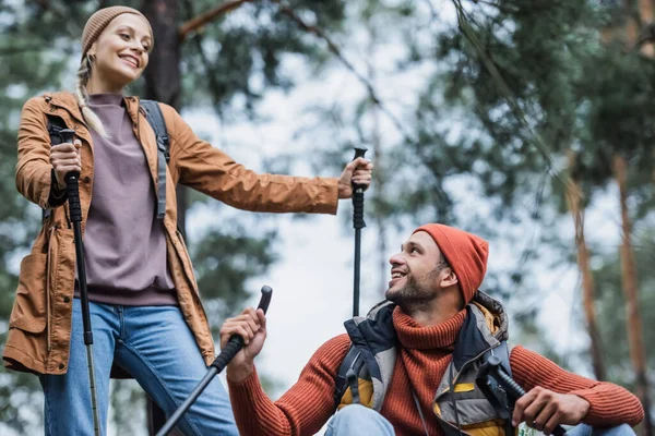 Couple heureux avec des bâtons de randonnée se reposant après trekking en forêt — Photo de stock