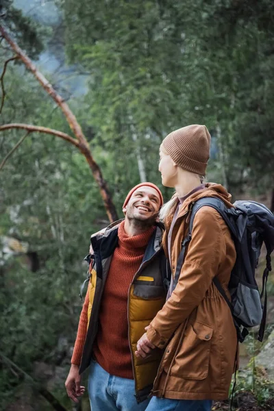 Junges und glückliches Paar hält Händchen, während sie sich im Wald anschauen — Stockfoto