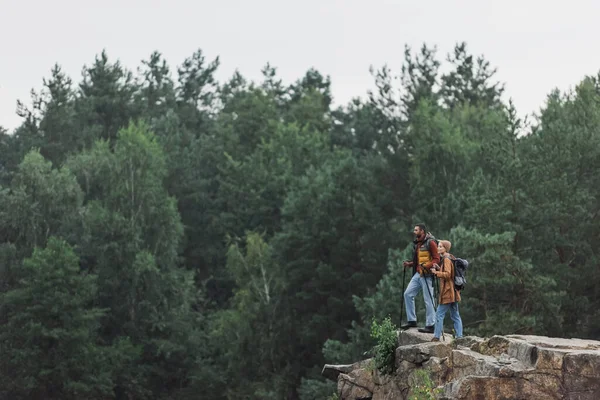 Couple with hiking sticks standing on rocky cliff — Stock Photo