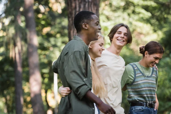 Sorrindo interracial adolescentes abraçando no parque — Fotografia de Stock