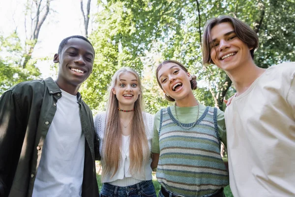 Adolescentes multiétnicos alegres olhando para a câmera ao ar livre — Fotografia de Stock