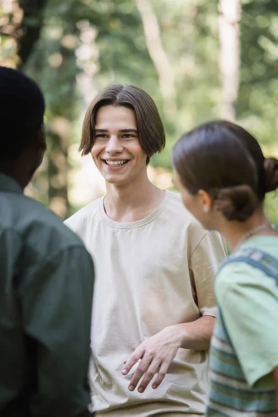 Adolescente sorrindo olhando para amigo afro-americano borrado no parque — Fotografia de Stock