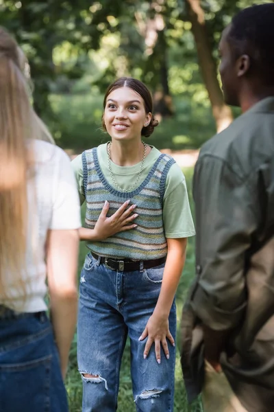 Joyeux adolescent fille parler à interracial amis en plein air — Photo de stock