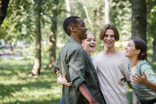 Happy interracial teenagers hugging in park — Stock Photo