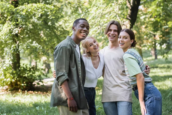 Multiethnic teenagers hugging and looking at camera in park — Stock Photo