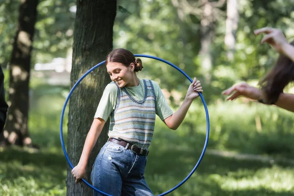 Smiling teenager holding hula hoop in park — Stock Photo