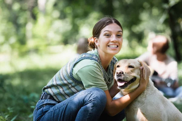 Souriant adolescent fille câlin récupérateur dans le parc — Photo de stock