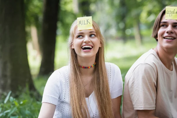 Smiling teenager with sticker playing who i am with friend outdoors — Stock Photo