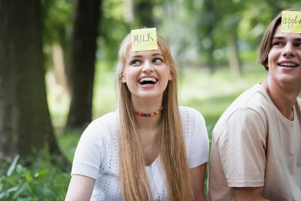 Sonriente adolescente con pegatina jugando quién soy con un amigo al aire libre - foto de stock