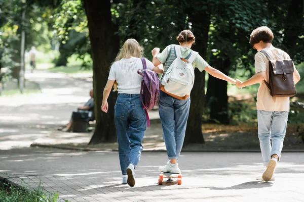 Adolescente chico cogido de la mano de amigo en el monopatín en el parque - foto de stock