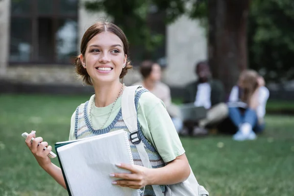 Étudiant souriant avec smartphone et ordinateur portable à l'extérieur — Photo de stock