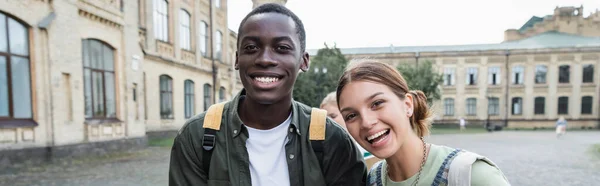 Sonriendo estudiantes interracial mirando a la cámara al aire libre, pancarta - foto de stock