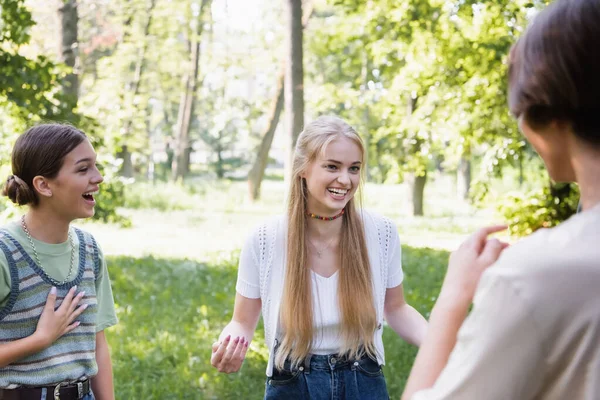Sonriente adolescente mirando borrosa amigo en parque - foto de stock