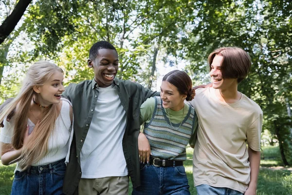 Interrassische Teenager lächeln und umarmen sich im Park — Stockfoto