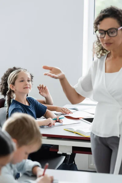 Professor afro-americano desfocado apontando com a mão enquanto conversava com alunos em sala de aula — Fotografia de Stock