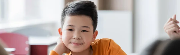 Asian schoolboy smiling at camera during lesson, banner — Stock Photo