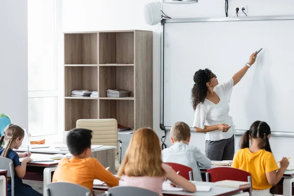 African american teacher pointing with felt pen at whiteboard during lesson — Stock Photo