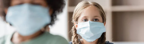 Selective focus of girl in medical mask near blurred african american boy, banner — Stock Photo