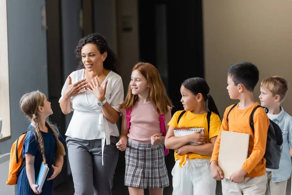 Enseignant afro-américain parlant à des écoliers souriants multiculturels — Photo de stock