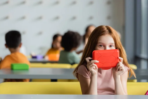 Rousse écolière obscure visage avec boîte à lunch dans la salle à manger — Photo de stock