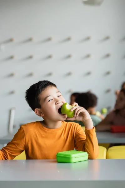 Asiatico scolaro mangiare mela in scuola mensa — Foto stock