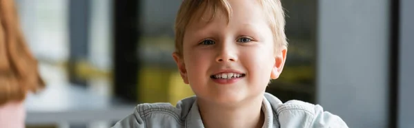 Menino da escola alegre sorrindo para a câmera durante a aula, banner — Fotografia de Stock