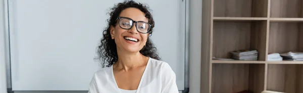 Gioiosa insegnante afroamericana in occhiali da vista sorridente in classe, striscione — Foto stock