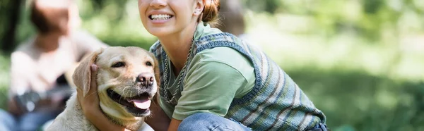 Recortado vista de adolescente sonriente abrazando retriever, bandera - foto de stock