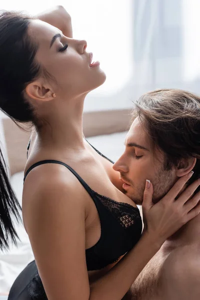 Side view of passionate man kissing body of seductive woman in bra — Stock Photo