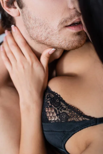 Close up of seductive girlfriend in black bra hugging boyfriend at home — Stock Photo