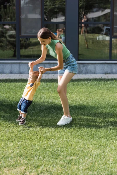 Full length of smiling mother holding hands with toddler son outside — Stock Photo