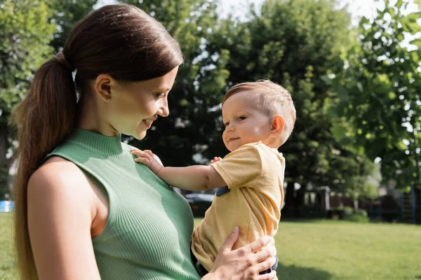 Alegre joven madre sosteniendo en brazos feliz niño hijo - foto de stock