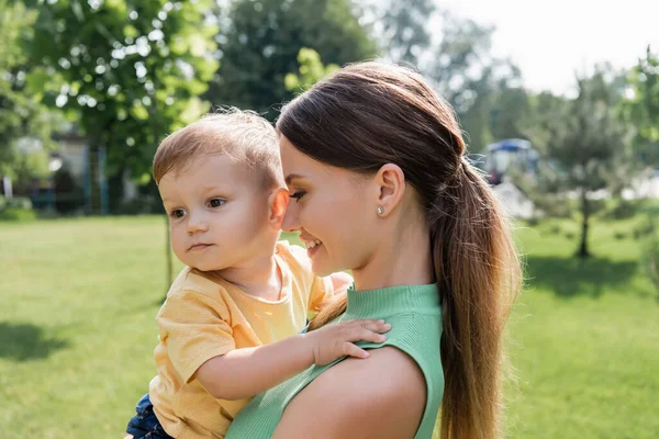 Cheerful young mother holding in arms toddler boy — Stock Photo