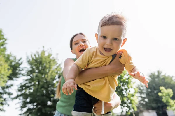 Offuscata e felice giovane madre in braccio stupito bambino figlio — Foto stock