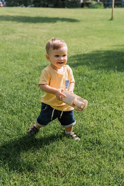 Fröhliche Kleinkind Junge mit Spielzeug Holzauto beim Gehen auf Gras — Stockfoto