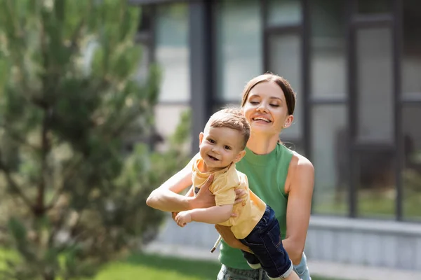 Cheerful and young mother holding in arms toddler son — Stock Photo