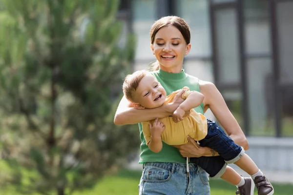 Souriant et jeune mère tenant dans les bras tout-petit fils — Photo de stock