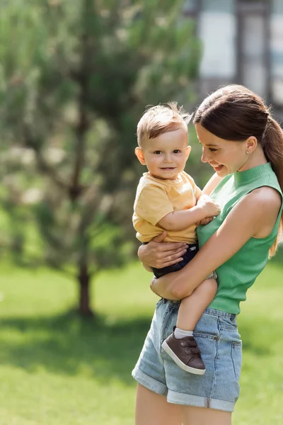 Gioiosa e giovane madre che tiene in braccio il figlio bambino — Foto stock