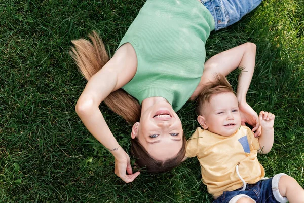 Vue du dessus de la mère heureuse passer du temps avec fils tout-petit heureux tout en étant allongé sur l'herbe — Photo de stock