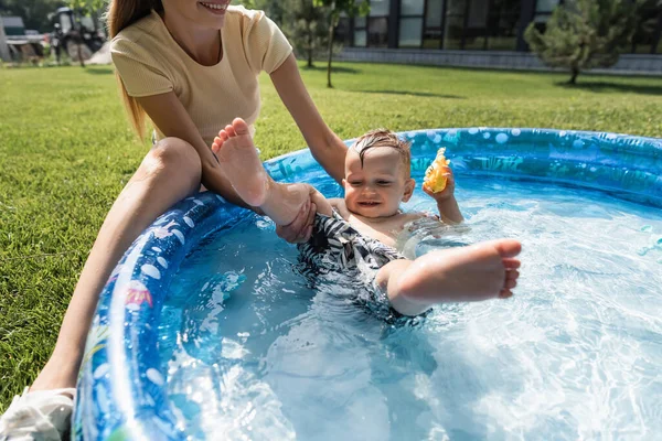 Felice madre che sostiene il figlio del bambino che nuota nella piscina gonfiabile — Foto stock