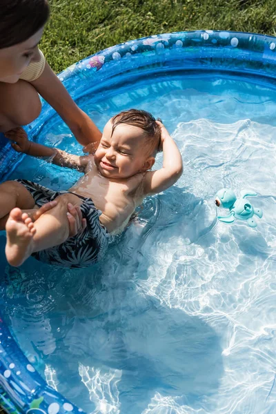Mutter stützt Kleinkind mit geschlossenen Augen beim Schwimmen in aufblasbarem Pool — Stockfoto
