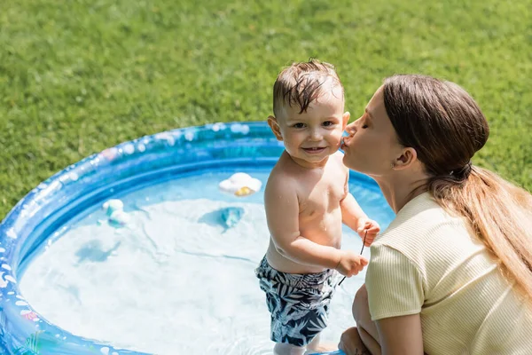Mère baisers joue de joyeux bambin fils dans maillots de bain — Photo de stock